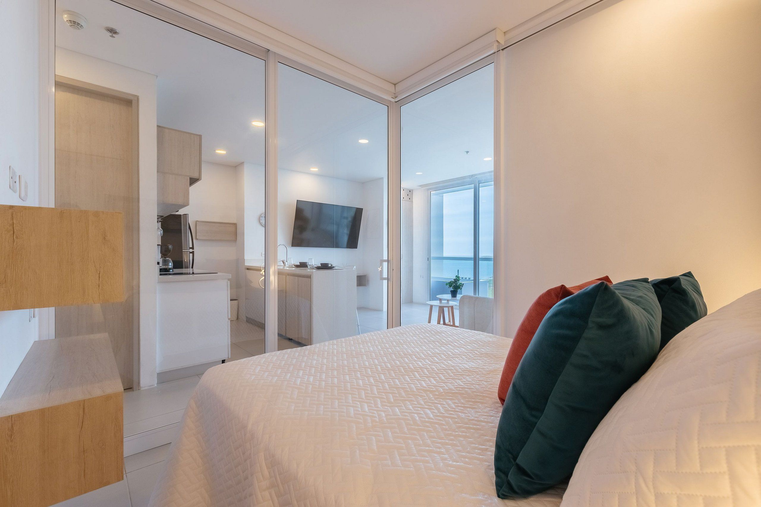 Quarto moderno com uma cama grande, uma mesa de escritório e vista para a cozinha e a sala de estar.