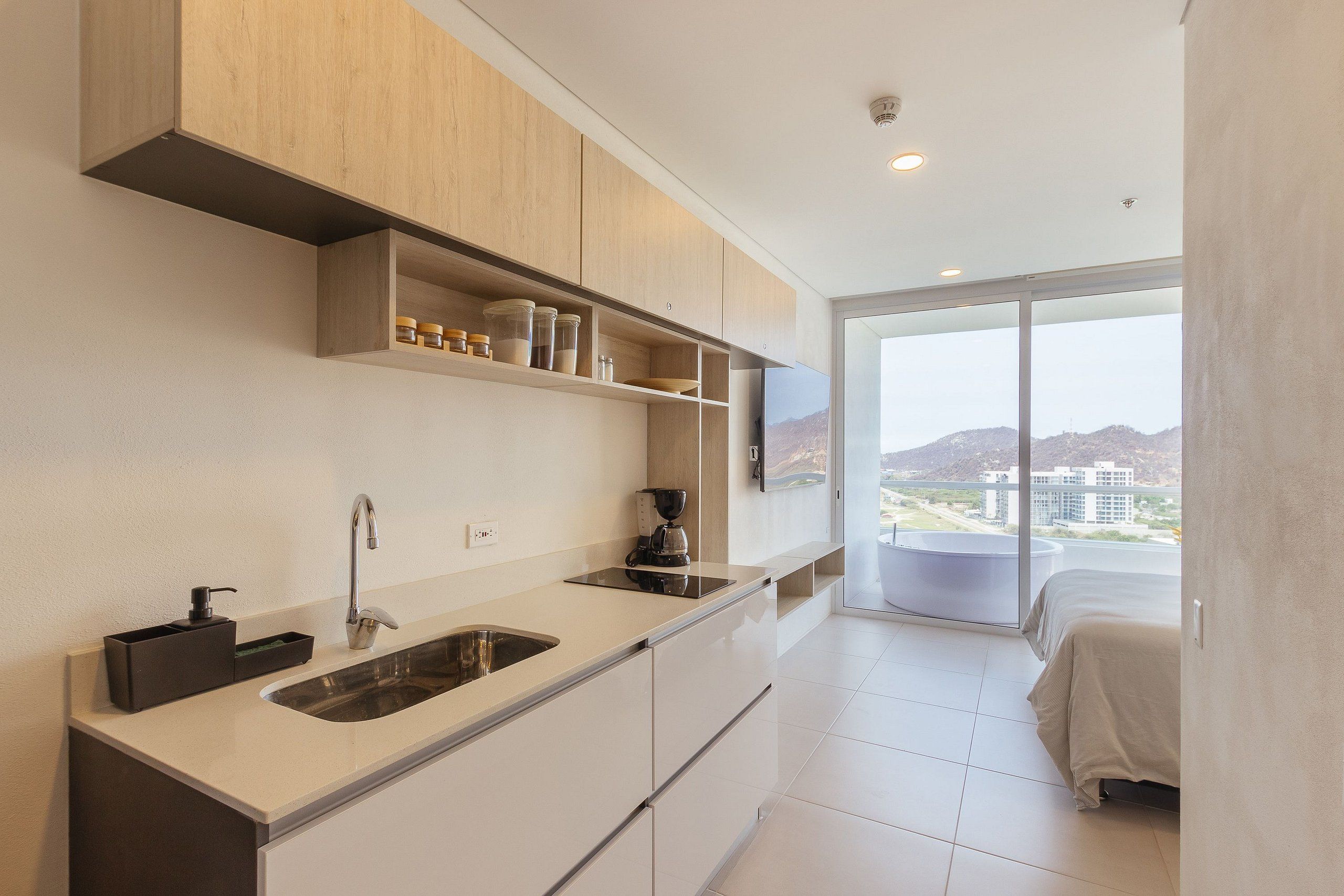 Una cocina moderna con un lavamanos integrado, una cafetera y vistas de la ciudad a través de amplios ventanales.