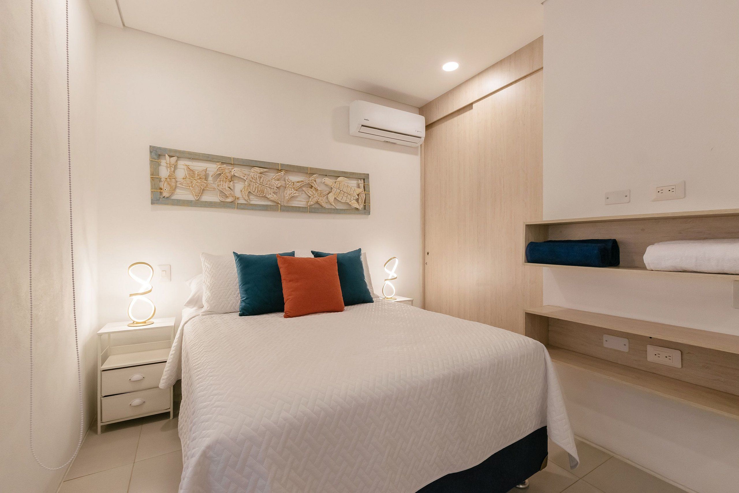 Une chambre d’hôtel équipée d’un lit, de tables de chevet, d’un climatiseur fixé au mur et d’un porte-serviettes.