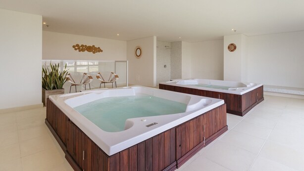 A spa area with two hot tubs, a seating area with chairs, and a large window. - U-GO Porto Horizonte Junto al Mar Sta Mta (Santa Marta)