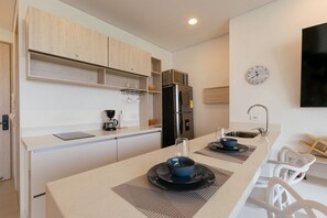 A modern kitchen with a built-in microwave, a refrigerator, and a coffee maker on the counter. - U-GO Porto Horizonte Junto al Mar Sta Mta (Santa Marta)