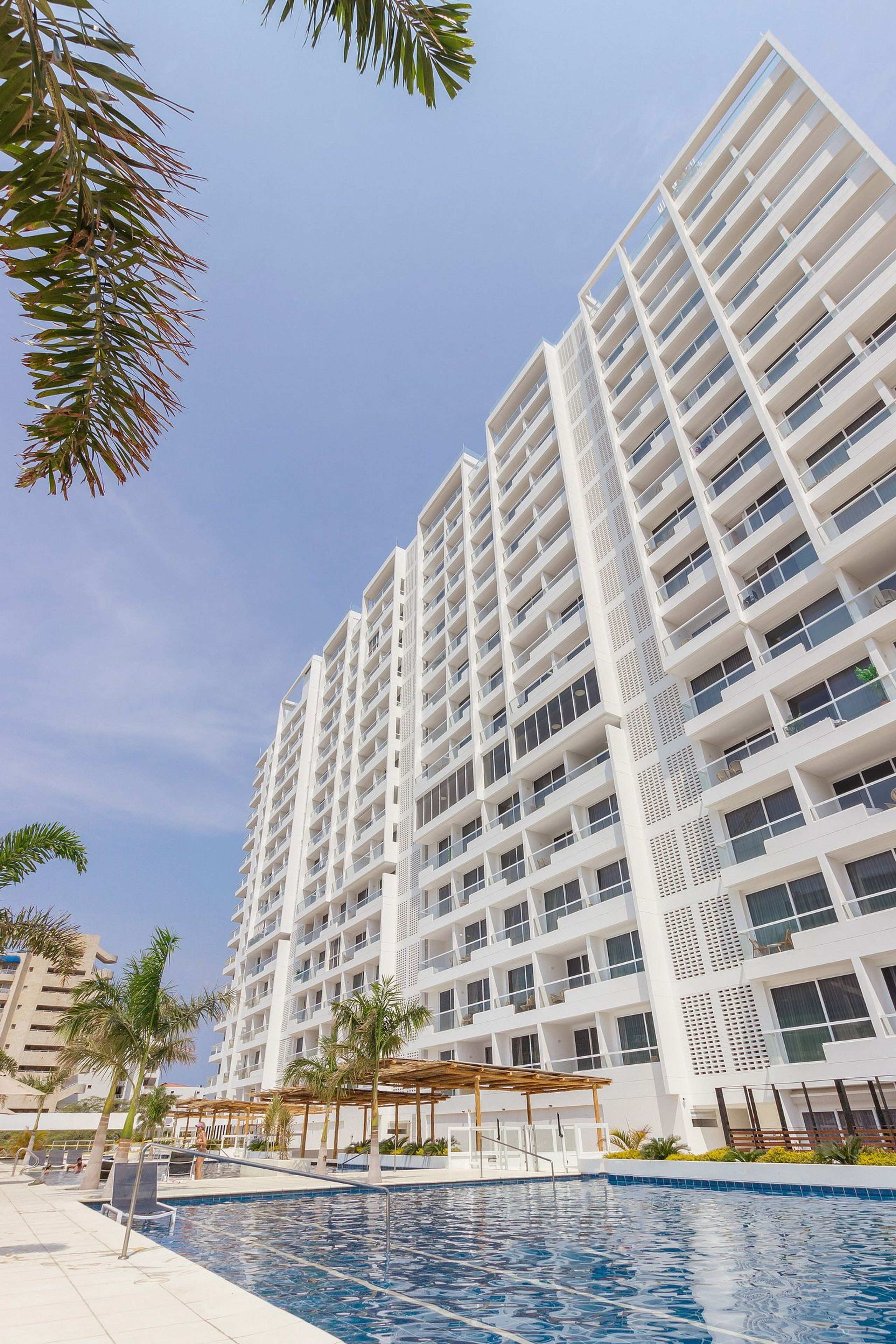 A high-rise hotel with multiple balconies and a swimming pool area.