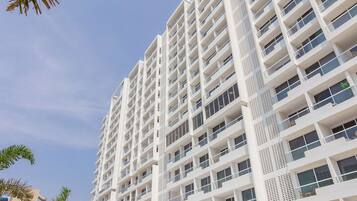 A high-rise hotel with multiple balconies and a swimming pool area.