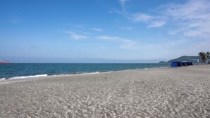 A beach with a clear sky, a red boat in the water, and a blue tent on the sand. - U-GO Porto Horizonte Junto al Mar Sta Mta (Santa Marta)
