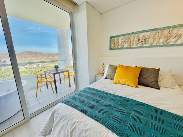A bedroom with a bed, a balcony with a table and chairs, and a view of the landscape. - U-GO Porto Horizonte Junto al Mar Sta Mta (Santa Marta)