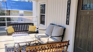 Eine Veranda mit einer Bank, einem Tisch und einem Schild mit der Aufschrift 'WELCOME'.