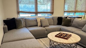 A modern living room with a sectional sofa, a round coffee table, and patterned rugs.