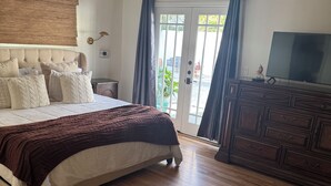 A bedroom with a bed, a ceiling fan, a dresser, and a television.