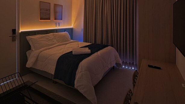 A modern hotel room with a bed, bedside table, and a TV.