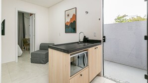 A modern kitchen with a built-in oven, a sink, and a dining area with a chair.