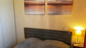 A bedroom with a bed, a nightstand with a lamp, and two wall-mounted paintings. - Titmouse, Gîte in Dordogne (Saint-Avit-Sénieur)