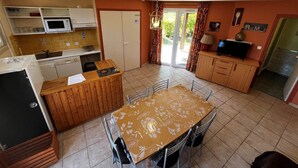 A compact kitchen with a dining area, a microwave, a sink, and a television. - Titmouse, Gîte in Dordogne (Saint-Avit-Sénieur)