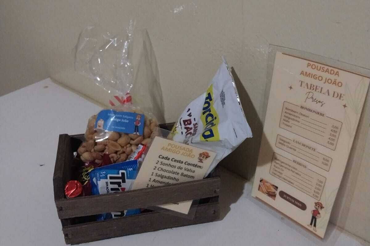 A wooden crate filled with assorted snacks and a menu on a table against a plain wall.