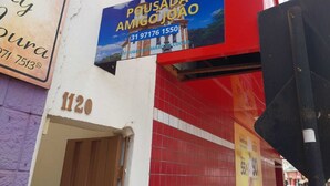 Un edificio con un cartel que dice 'Pousada Amigo Júnior' y un número de contacto.