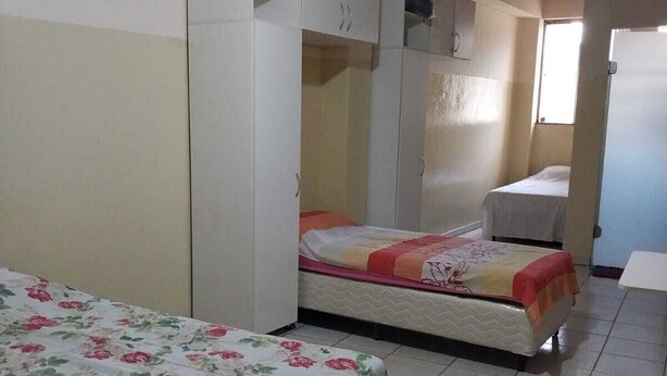 Un dormitorio con cama, armario y mesita de noche.