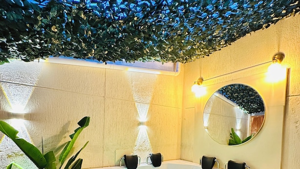 Un cuarto de spa con una bañera grande, un espejo y una planta.