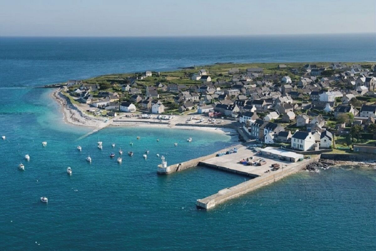 An aerial view of a coastal town with a marina, houses, and a beach.