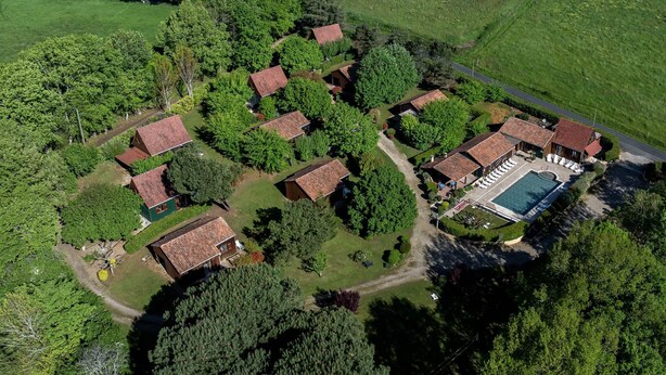 An aerial view of a residential area with multiple houses, a swimming pool, and surrounding greenery. - Pinson, Gîte with outdoor spa ideal for couples (Saint-Avit-Sénieur)