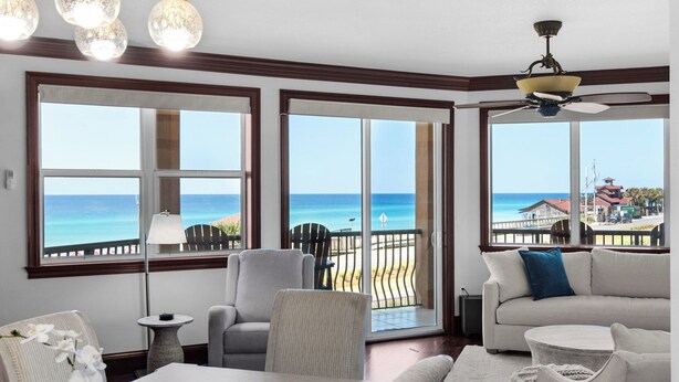 A room with large windows offering a view of the ocean, a ceiling fan, and a dining area with a table and chairs. - Gorgeous Condo at Mediterranea! (Miramar Beach)