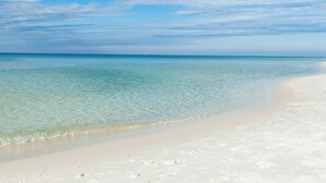 Una playa con aguas transparentes y poco profundas, y una orilla arenosa.