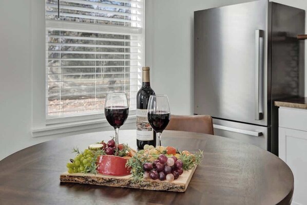 A dining table with a charcuterie board, two glasses of red wine, and a bottle of wine.