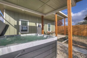 A hot tub under a covered patio with wooden beams, a wooden fence, and a house with a window and door. - Evergreen Escape: Hot-Tub,5 Min Downtown! (Fredericksburg)