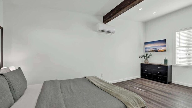 Un dormitorio con cama, cómoda, ventana con persianas y equipo de aire acondicionado.