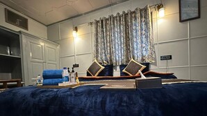 A bedroom with a large bed, a wardrobe, a desk, and a chair. - WATERFRONT PINE PAHALGAM (Anantnag)