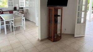 Una habitación con una mesa de comedor y sillas, un televisor sobre un mueble de madera, y una puerta que da al exterior.