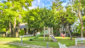 A park with a wooden play structure, a green slide, and white benches. - Newly Reformed Marbella Real Two Bedroom Apartment (Marbella)