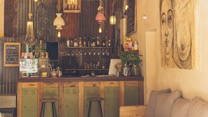 A bar area with wooden lockers, hanging lights, and a large abstract painting on the wall. - Hostel Pura Vida Mae (Yerba Buena)