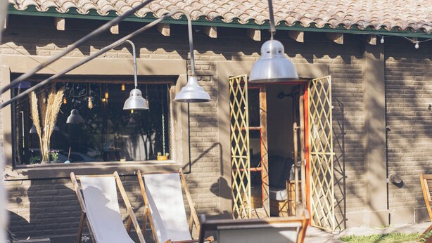 A courtyard with outdoor seating, a brick building, and hanging lights. - Hostel Pura Vida Mae (Yerba Buena)