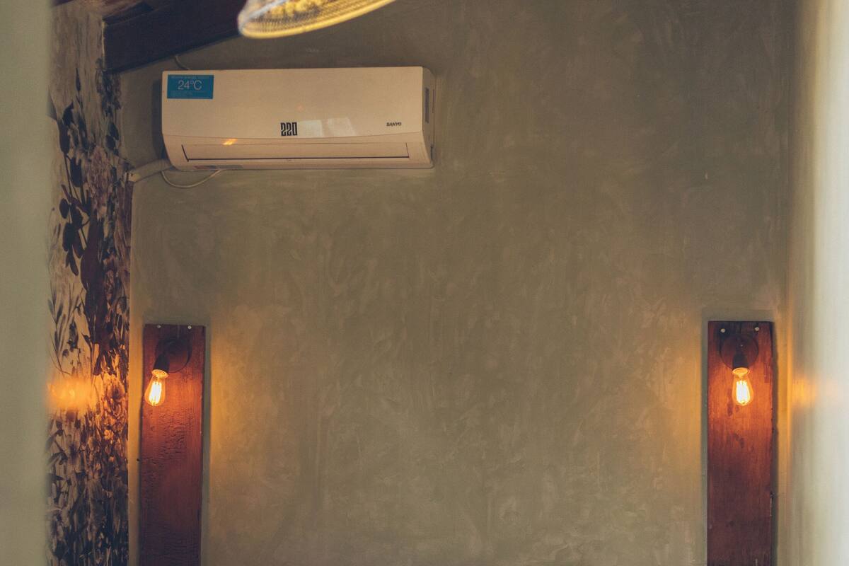 Een knus slaapkamer met een bed, een wandairconditioner en twee wandlampen.
