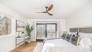 A bedroom with a bed, a desk, a ceiling fan, a window, and a balcony. - Lake Point Escape - Dock and Hottub on Belews Lake (Forsyth County)
