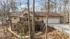 A two-story house with a stone foundation, a garage, and a wooden deck. - Lake Point Escape - Dock and Hottub on Belews Lake (Forsyth County)