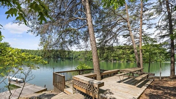 A wooden deck with benches overlooking a lake, surrounded by trees. - Lake Point Escape - Dock and Hottub on Belews Lake (Forsyth County)