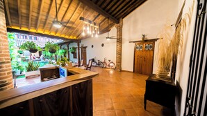 A spacious kitchen with a wooden counter, hanging plants, and a bicycle in the background. - BOHEMIA HOTEL BOUTIQUE  (Mompos)