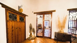 A wooden door with decorative metalwork, a small potted plant, and a lamp on a wooden table. - BOHEMIA HOTEL BOUTIQUE  (Mompos)
