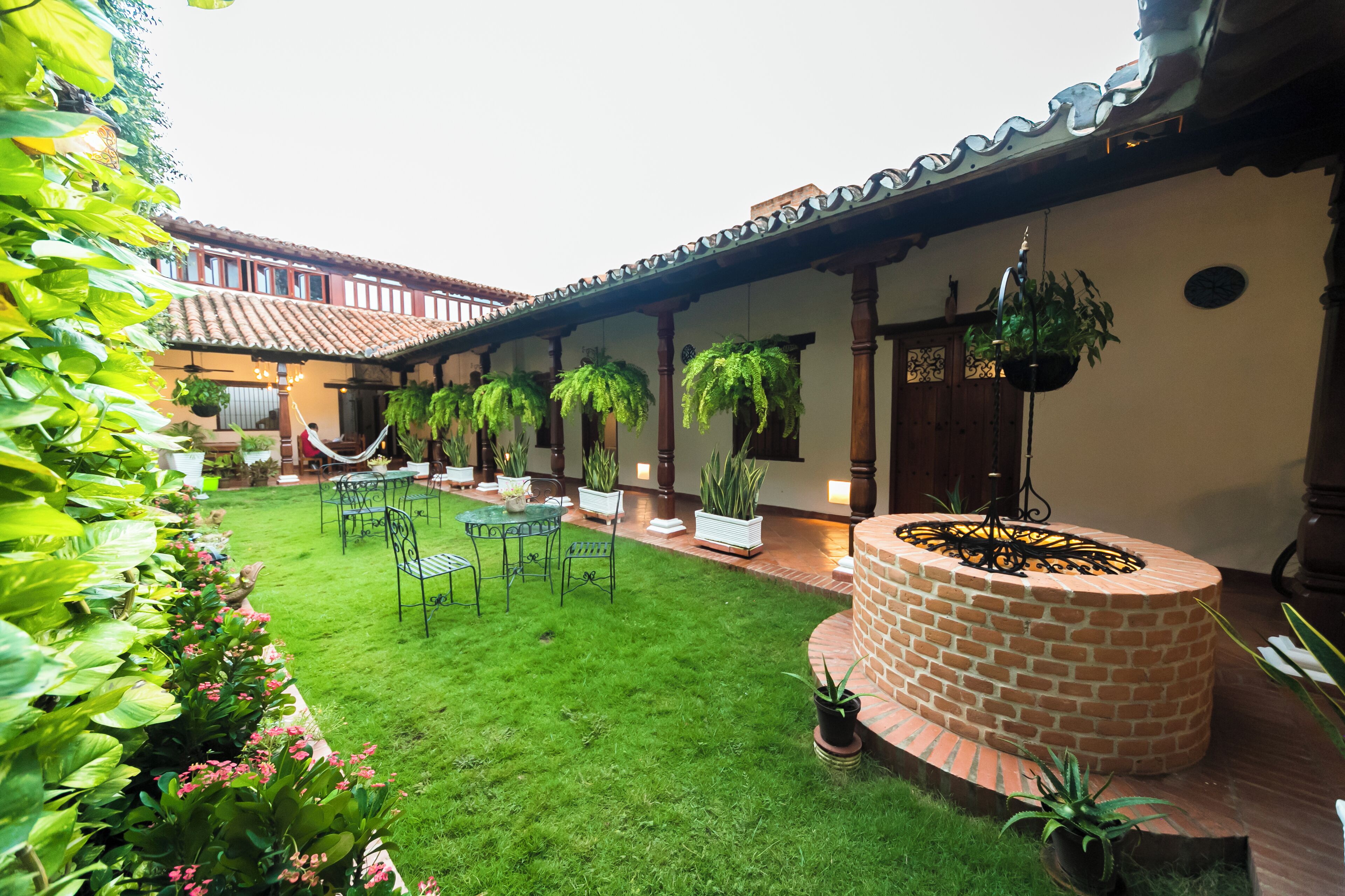 A courtyard with a brick fire pit, hanging plants, and a seating area with tables and chairs.