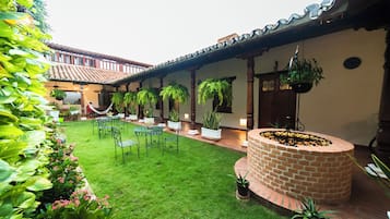 A courtyard with a brick fire pit, hanging plants, and a seating area with tables and chairs.