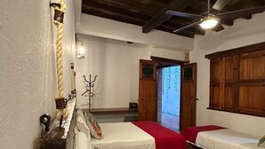 A room with two beds, wooden beams on the ceiling, a ceiling fan, and a window with a view. - BOHEMIA HOTEL BOUTIQUE  (Mompos)