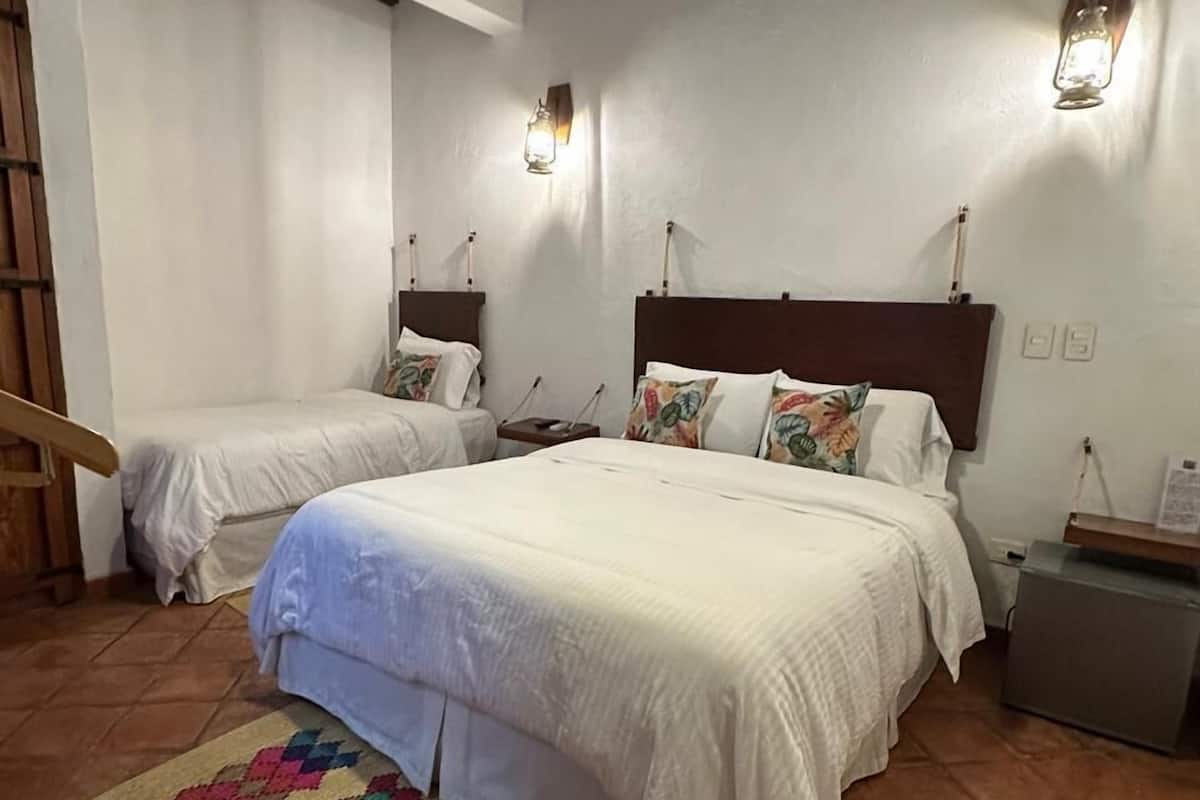 A bedroom with a large bed, two bedside tables, a ceiling fan, and a patterned rug.