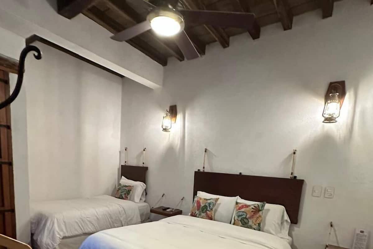 A bedroom with two beds, a ceiling fan, a nightstand, and a rug.