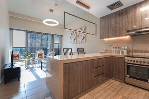 A modern kitchen with a central island, built-in oven, and large windows offering a city view. - Stunning Lake View 1BHK Retreat in Dubai (Dubai)