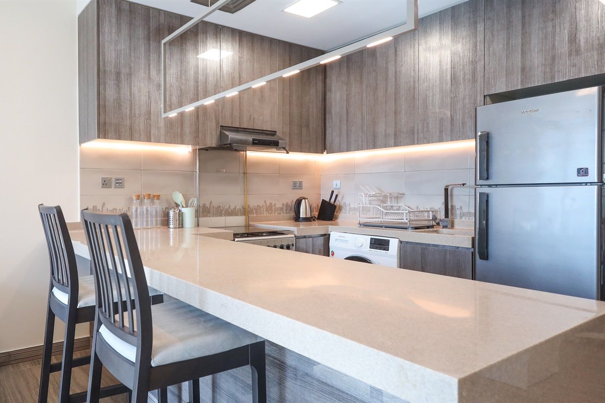Een moderne keuken met een groot eiland, roestvrijstalen apparatuur en houten keukenkastjes.