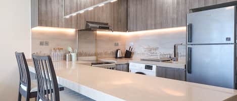Een moderne keuken met een groot eiland, roestvrijstalen apparatuur en houten keukenkastjes.