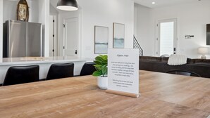 Una cucina moderna con un tavolo da pranzo in legno, sedie nere e lampade a sospensione.