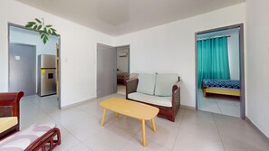 Une pièce comprenant un canapé, une petite table, un lit et un miroir.