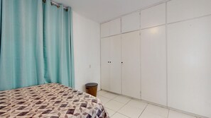 Une chambre à coucher avec un lit, une armoire et une poubelle.