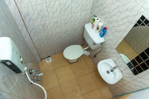 Bathroom features a toilet, sink, and shower area with toiletries on the toilet tank.